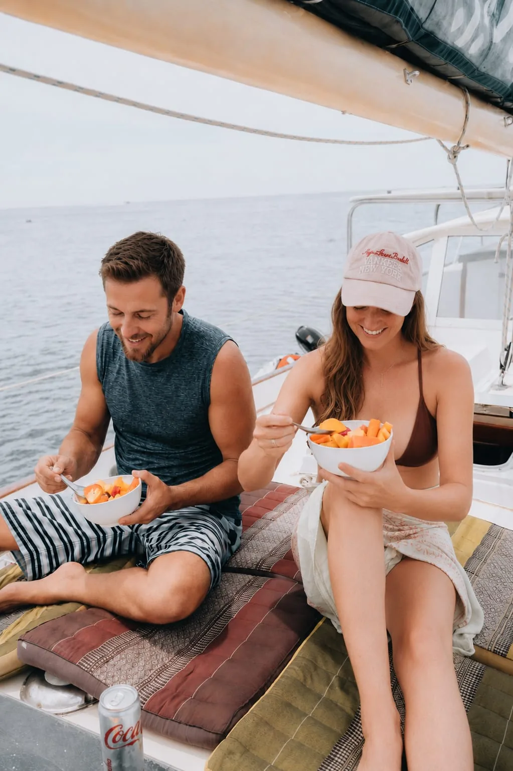 A couple sharing fresh fruit bowls on the deck cushions of SV Freedom Fargo