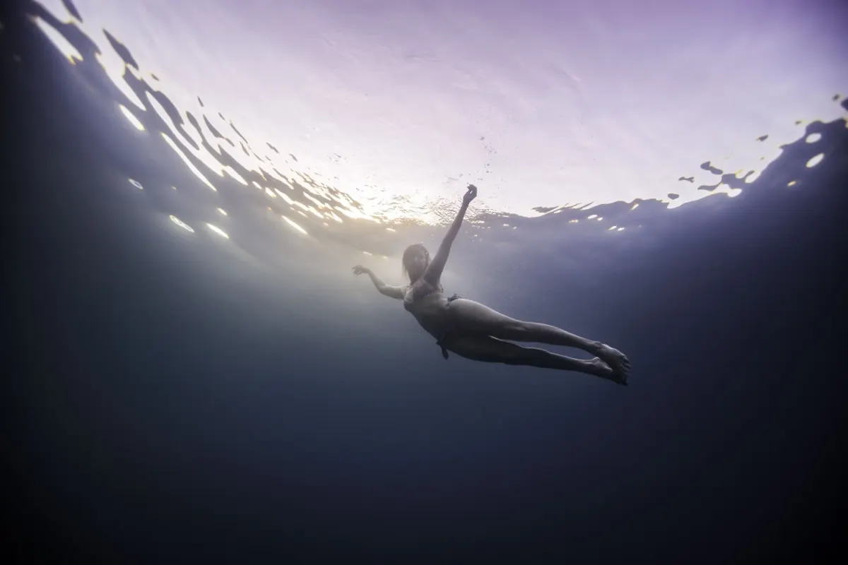 Freediver gliding just beneath the surface in the soft light of the end of the day